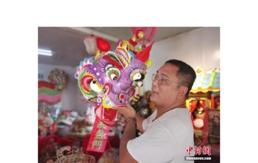 香港扎作师傅冒卓祺向记者介绍麒麟头的艺术特点。