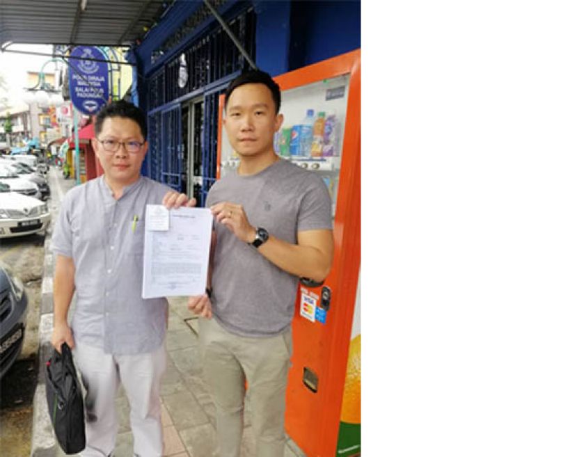 团长郑志国（左）与秘书符顺顺展示报案书。