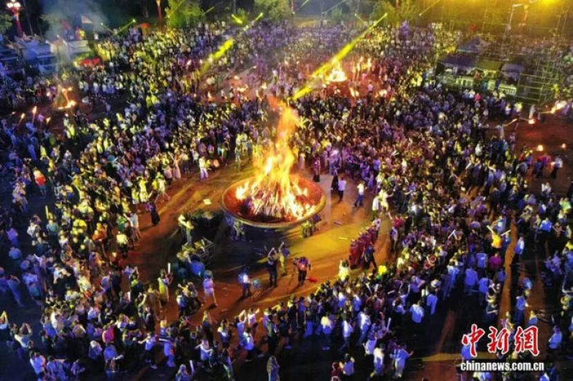 2025年7月18日火把节期间，云南楚雄，海内外游客围着篝火载歌载舞，欢庆火把节。