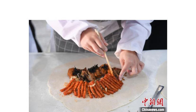 工作人员将辣条及肉馅包入饺子。