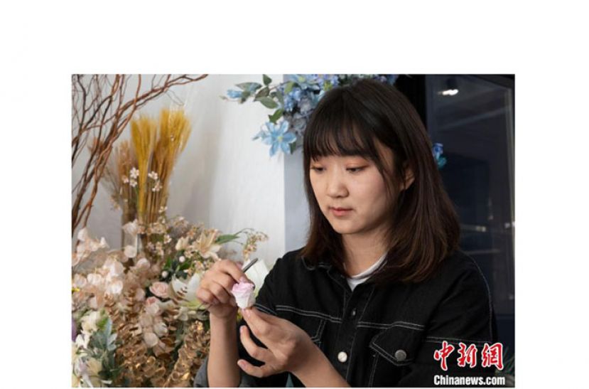 马媛正在处理一朵永生花。