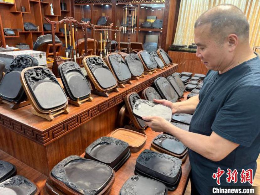 蔡三洪在观赏自己雕刻的端砚作品。