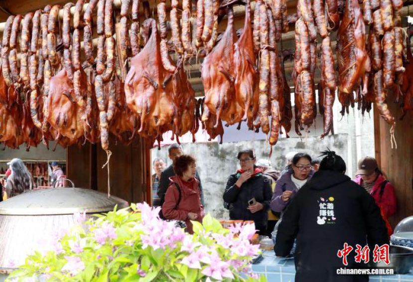 在广西三江侗族自治县丹洲古镇，游客在选购当地腊味产品。