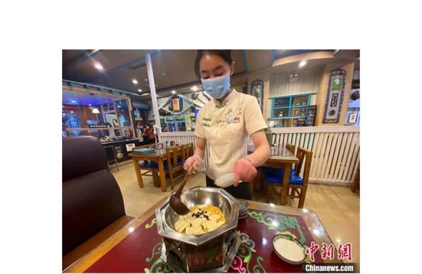 呼和浩特市一家奶茶店里，服务员萨拙拉将黄油、炒米等奶茶&ldquo;伴侣&rdquo;放入热锅中。