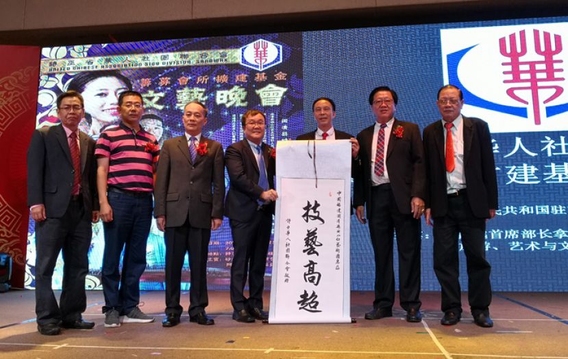 中国闽清县映山红艺术团在诗巫省华人社团联合会邀请下到诗巫演出，为华团会所扩建工程募款。华团副会长兼筹备会主席许忠全（左四）将一面&ldquo;技艺高超&rdquo;的条幅移交给闽清县人民政府办公室主任科员方文标（左五）。左一起是华团会所扩建筹委会主席苏少萃，映山红艺术团领队聂志武，中国驻古晋总领事馆领事程洪。右一及二是华团署理会长刘锦虎，会长严榀胜。