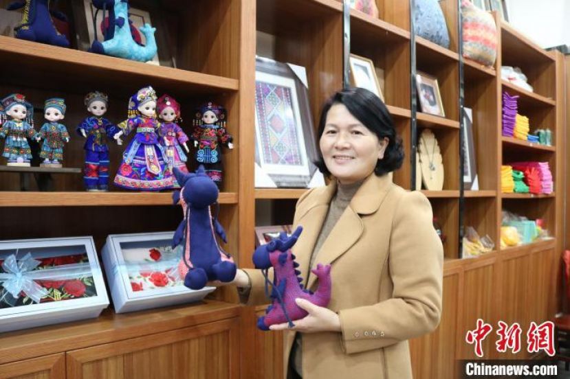 李村灵展示靖西市壮锦厂生产的壮锦龙宝布偶。
