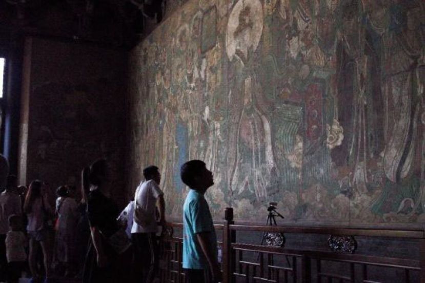 游客在山西运城市芮城县永乐宫内观看壁画。