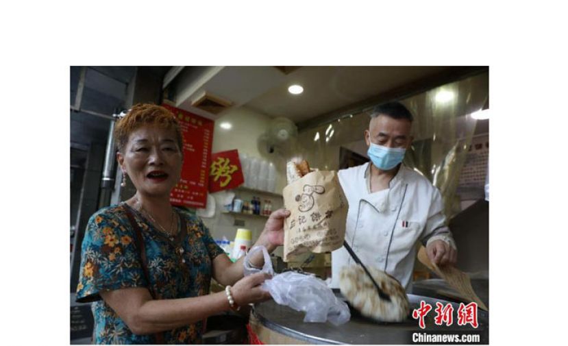 一位老顾客来到应晓伟的烧饼店买饼。