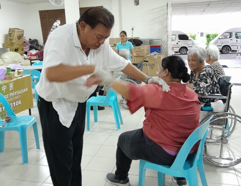 陈中兴医师在平安之家义诊为一名肩膀酸痛女士做推拿理疗。