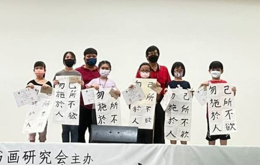 初小组入选者在展示作品时与古晋区赛主办单位的古晋中华书画研究会会长沈捷平（右三）及筹委会主席蔡晋利（左三）合影。