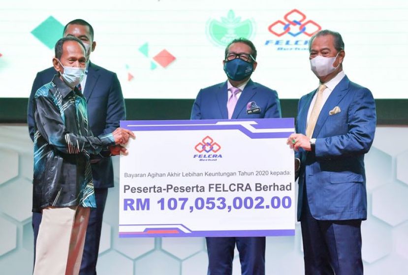 慕尤丁（右起）在阿都拉迪夫的见证下，颁发联邦土地统一及复兴局红利模拟支票予代表。