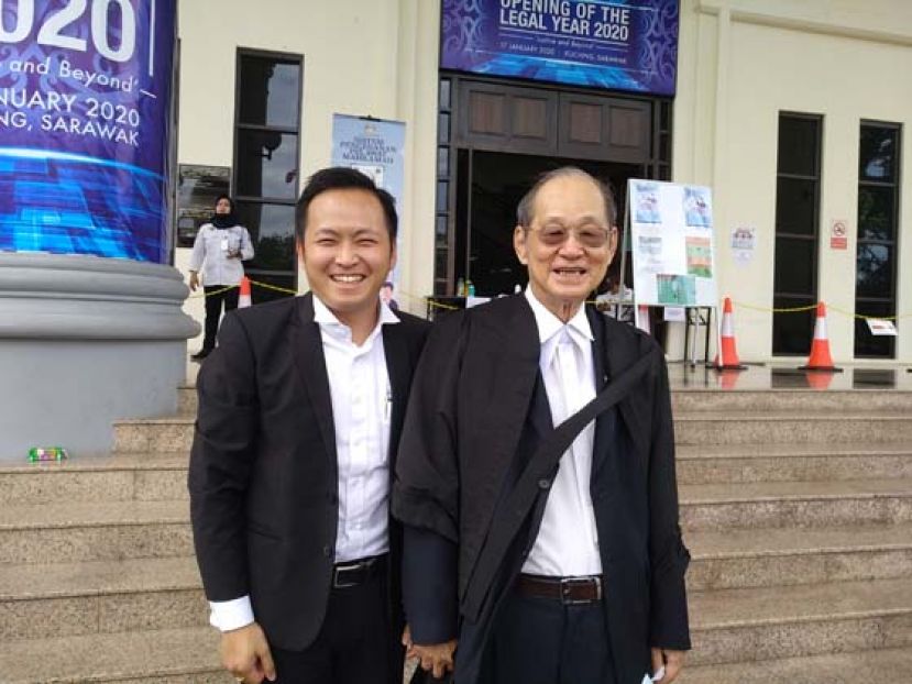 张守江（右）和江峰年影于法庭大门前。