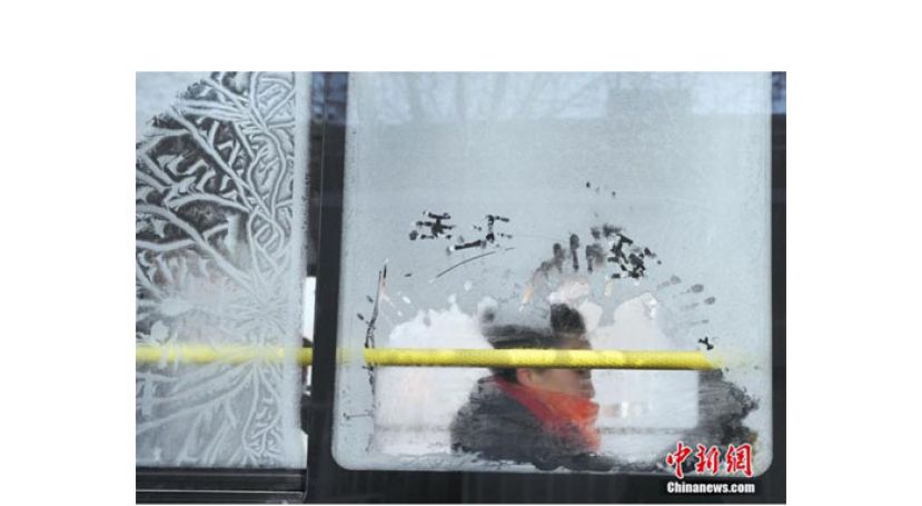 一位女乘客坐在凝结出冰花的车窗旁，当日是大寒节气。