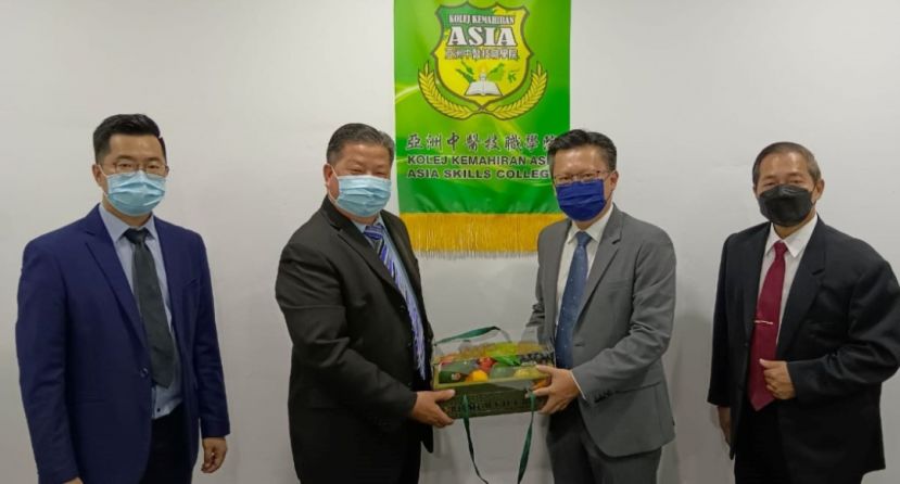 砂医总会长兼亚洲中医技职学院院长江宗兴（左2）赠水果礼蓝予武吉阿瑟区州议员钱进一。右一为监考本固鲁蔡雄基；左一为该学院主任江邦忠。