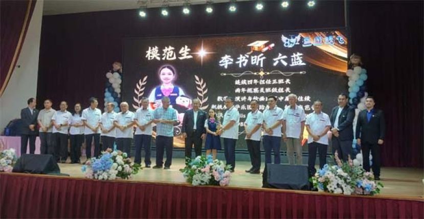 在校董和嘉宾们的陪同下，古晋中华小学校董会主席蔡文铎(右七)颁奖模范生奖予六蓝班的李书时影。