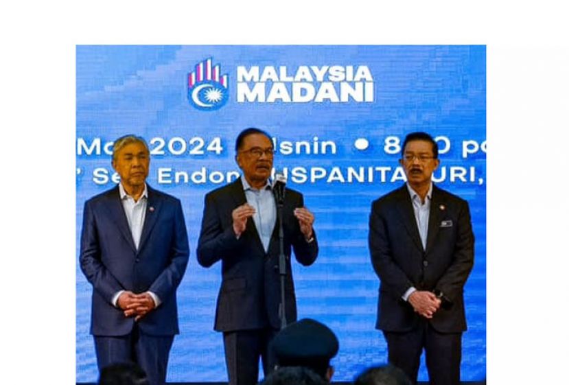 首相安华(中)在首相署常月集会上致词。左为副首相阿末扎希，右是政府首席秘书祖基。