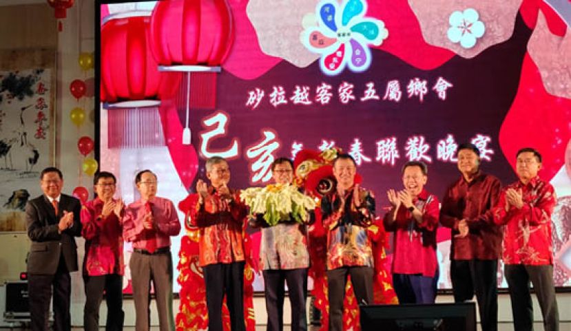 图示：砂首长拿督巴丁宜阿邦佐哈里（中）展示从瑞狮口中接的过福品，右起为晋汉省大埔同乡会暑理主席蓝里安、砂古晋嘉应同乡会会长陈晋宗、砂地方政府与房屋部长拿督沈桂贤、砂河婆同乡会主席张添堡；右起古晋惠东安公会会长周运华、砂客属公会会长刘贵梦、古晋会宁同乡会主席梁明光及晚宴筹委会主席拿督蔡庆忠博士。