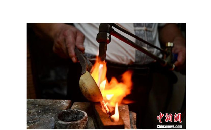 吴共能在用火枪煅烧银子，倒入槽中。