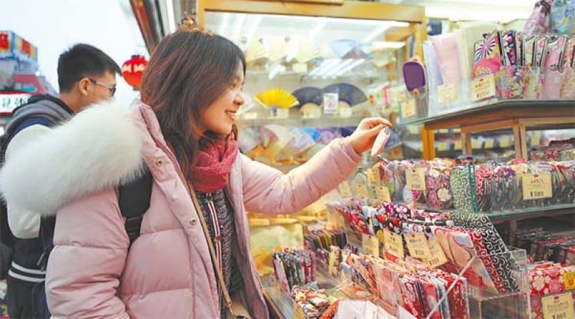  中国游客在东京浅草的商店街选购商品。