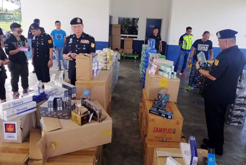 陈协成助理总监(中)查看下属起获的漏税烟酒。