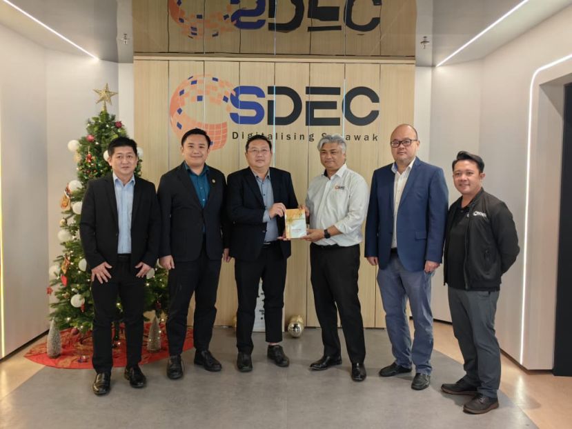 全体照摄于SDEC位于Satok的办事处。王运才教授（左三）赠送砂中总手册予Dato Ir. Ts Sudarnoto（右三）。左起一蔡明龙、左二陈政信。右起一Mr. Khairool，右二沈铂斯。