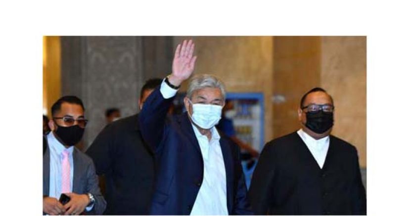 仍官司缠身的阿末扎希周一在法庭外向媒体挥手示意。