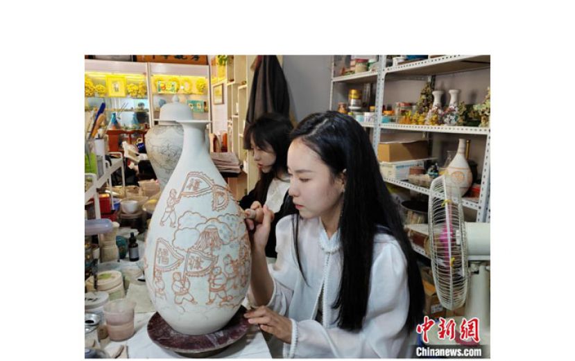 记者见到张珺靓时，她正坐在工作台前，身体微微向前倾，用工具在素坯上沥线。