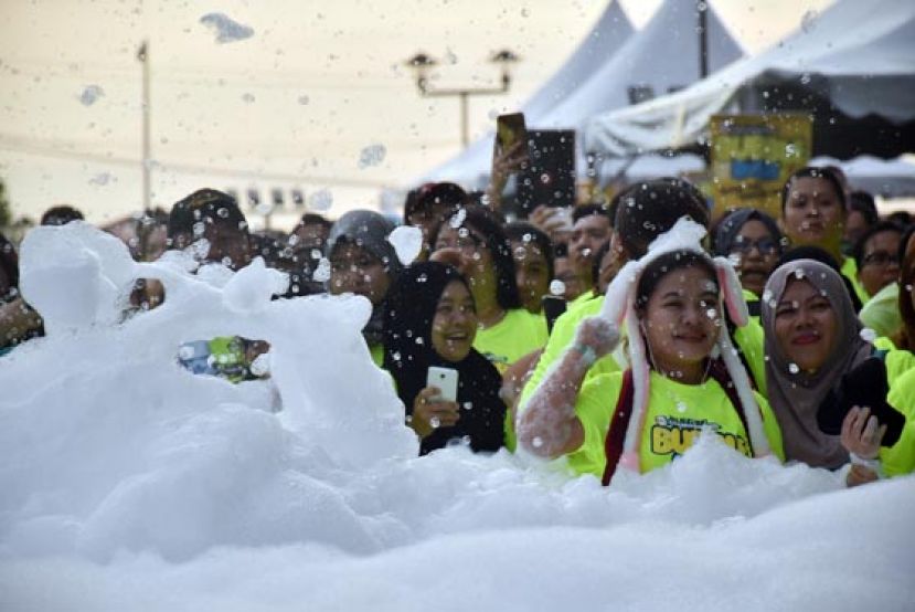 &ldquo;泡沫&rdquo;慈善义跑参与者童心未泯的玩起堆积在起跑点的泡沫。