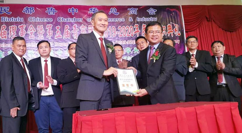 李开运(右)为新届理事主持监誓后，移交宣誓书予民都鲁中总会长叶绍良。