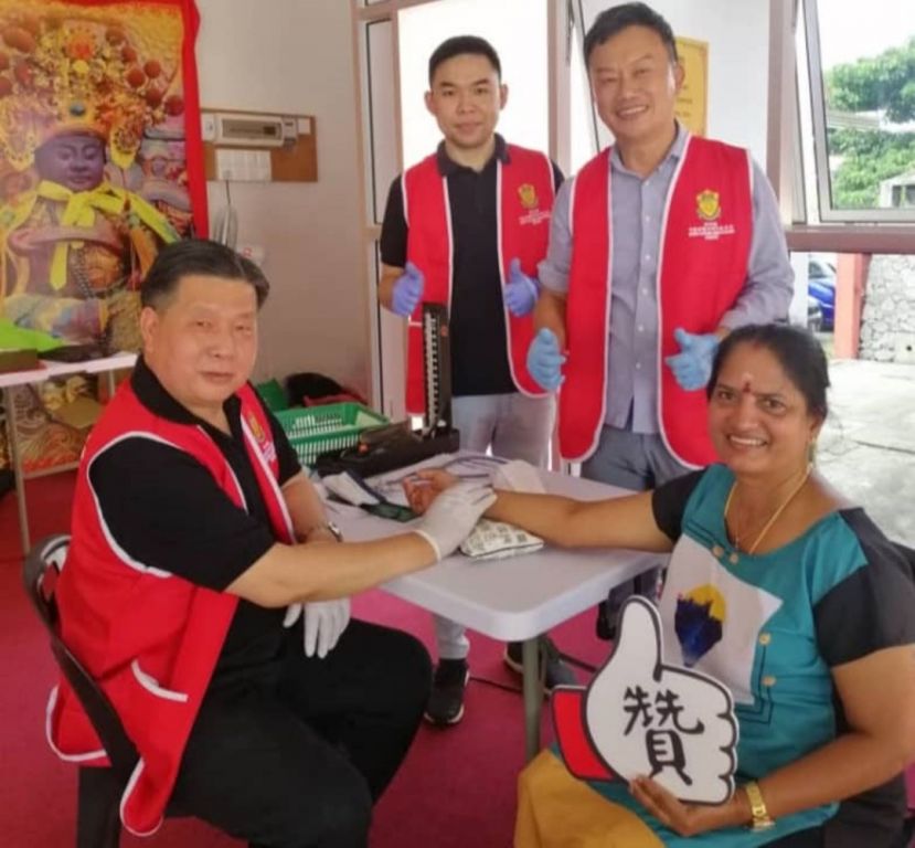 砂医总会长江宗兴（左）在中医义诊为印度裔女士诊脉；左2起为刘子荣医师、沈燕东医师。