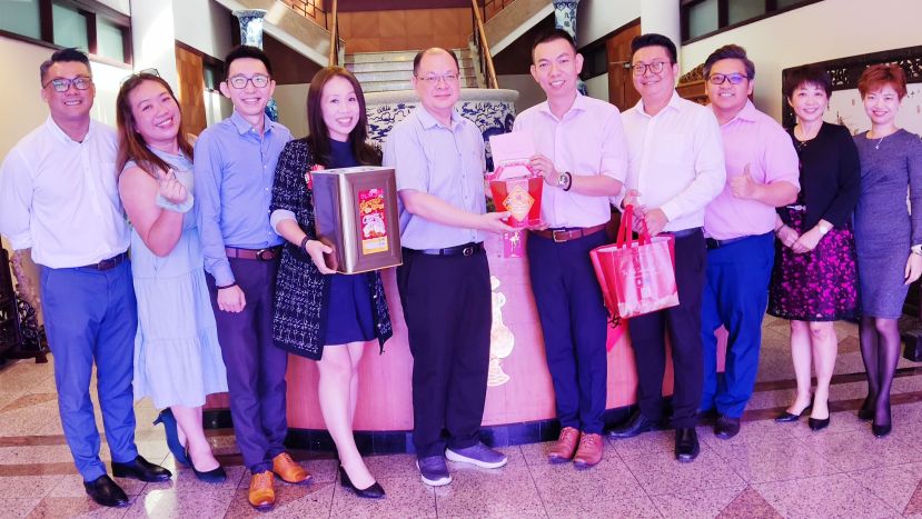 宏源理财理财规划师罗嵱惠（右五）移交新年礼品予国际时报业务发展经理陈朝忠（左五）。