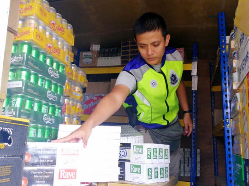 警员在货柜车箱内，点算缴获的漏税烟酒。