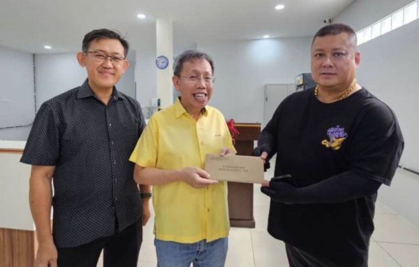  诗山凤山寺威灵殿神诞筹委主席田丙辰（右）移交主宾函予沈桂贤副总理；左为该殿顾问薛华东。