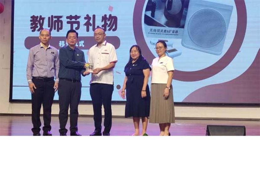 古晋中华小学校董会副秘书长郑国栋（中）赠送教师节礼物，由校长黄玉祥接收时摄。