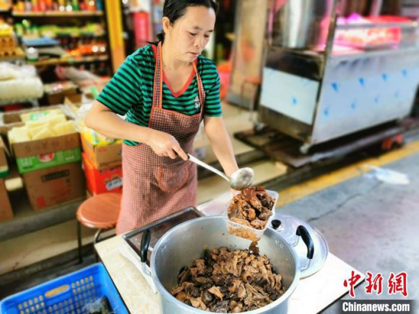 台山市台城富城市场一熟食摊的老板娘为顾客打包焖番鸭。