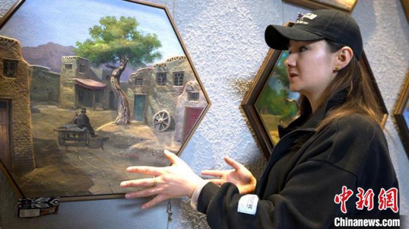 古努&middot;阿里根向记者介绍她的彩石画。