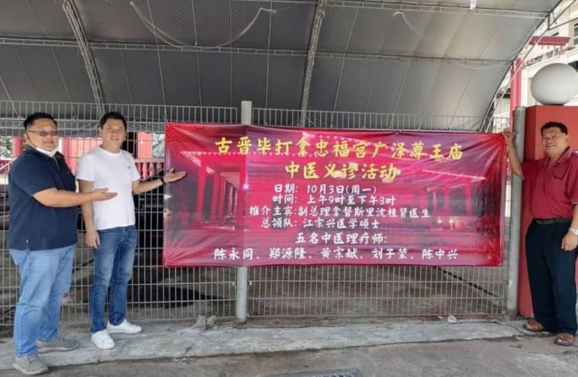 古晋毕打拿忠福宫广泽尊王庙中医义诊筹委主席张荣华（左起）、秘书马可倧，以及砂医总会务顾问陈中兴在该庙前展示义诊布条。