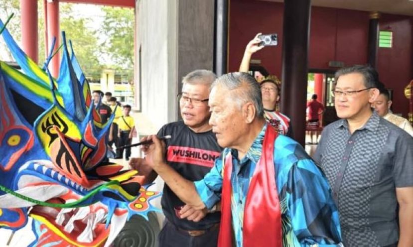 拿督杨昆贤（中）为古晋武术龙狮协会的一支龙队龙头进行&ldquo;点睛开光&rdquo;，左为该会署理会长郑李金春：右是薛华东。