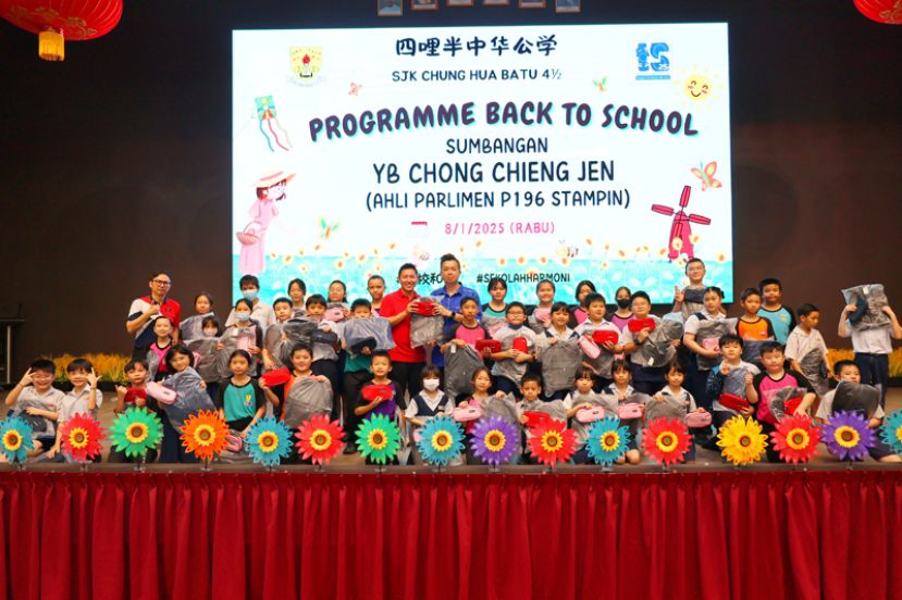 实旦宾区国会议员张健仁特别助理沈杰龙（第二排左八）移交新书包及新文具给《实旦宾区返校计划》其中一所学校-四哩半中公校长张钦华（第二排左九）。