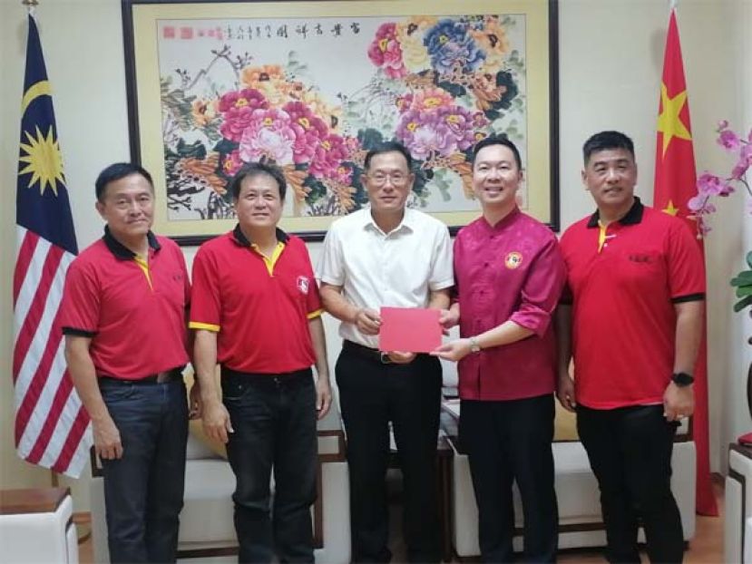 古晋东嶽观庆典筹委主席吴志鸿（右2）移交上宾邀请函予邢伟平总领事（中）。右为郑汉雄；左起是钟献忠、方文祥太平局绅。