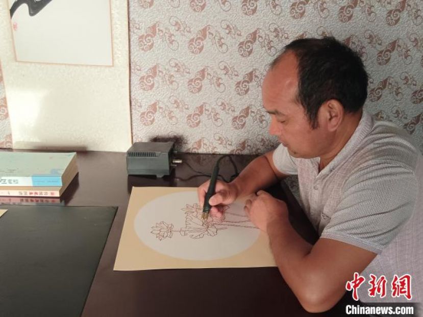 庄会锋正在以烙铁为笔、烙痕为墨，绘出一幅栩栩如生的图画。