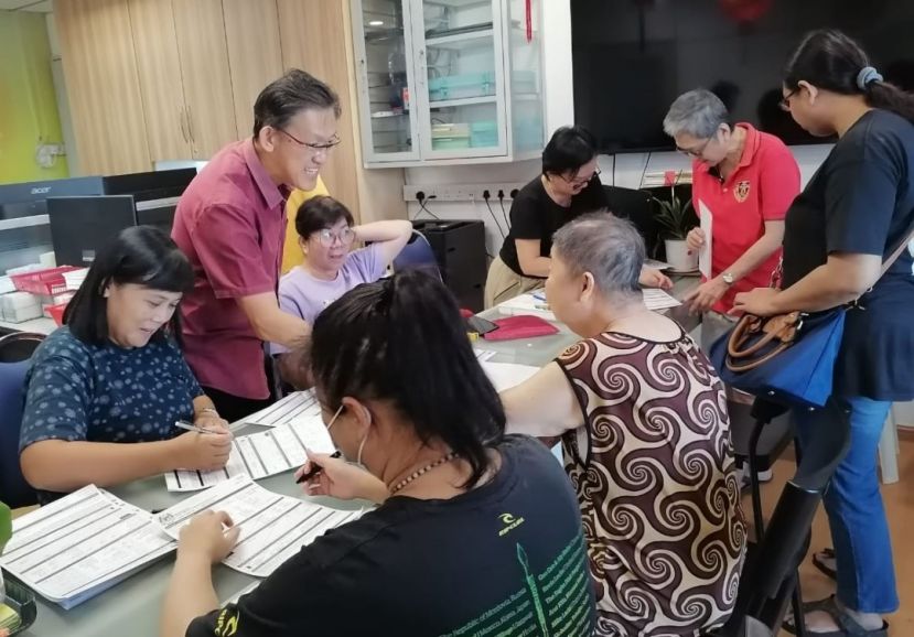 薛华东（左2）与其团队在人联党峇都林当支部助低收入群体填写援金申请表格。
