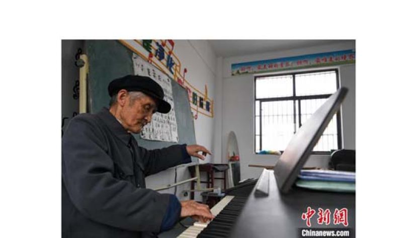严明友在朱湾小学音乐教室里弹奏歌曲。