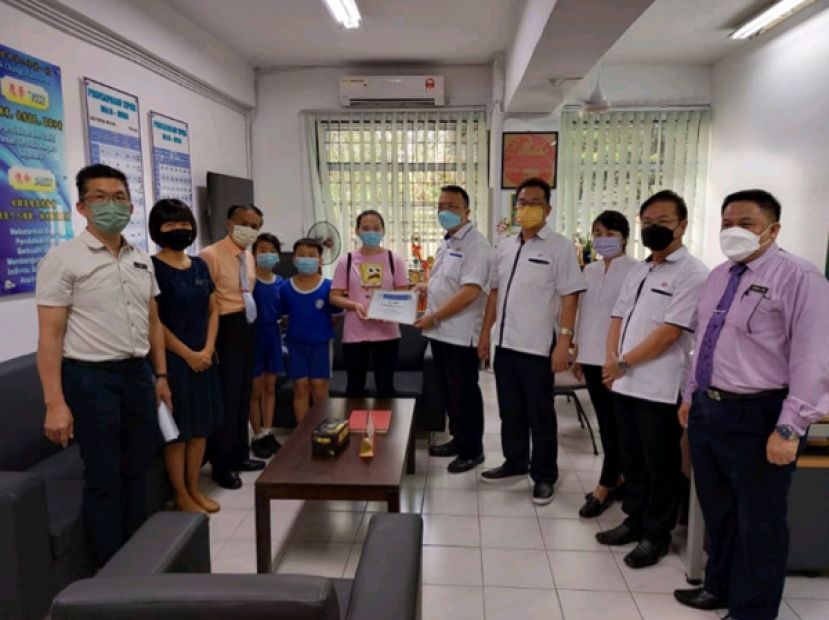 古晋中华小学校董会主席拿督蔡文铎（右五）移交爱心捐款予詹太太。右起是一小萧家宝副校长、校董会副财政周天龙、校董会副财政罗绍凤、校董会秘书长田松茂；左起是方秉发副校长、沈俐利副校长、校长李美发。