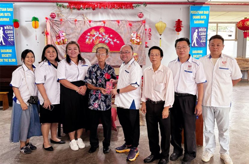 善心组织副会长甲必丹拿督刘思乐（右4）移交红包予砂盲人协会古晋分会主席Ronald Law。左起为义工郭燕珠、陈俐玲、蔡凌、右起为义工文朝龙、理事田志和及蔡新锐。