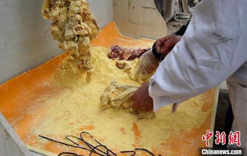 给羊肉涂抹上金黄色纯天然的玉米面，让其充分融合。