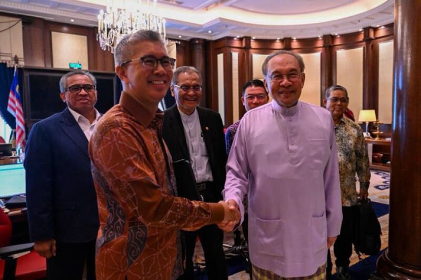 首相安华与东姑扎夫鲁握手，感谢他对国家的贡献。