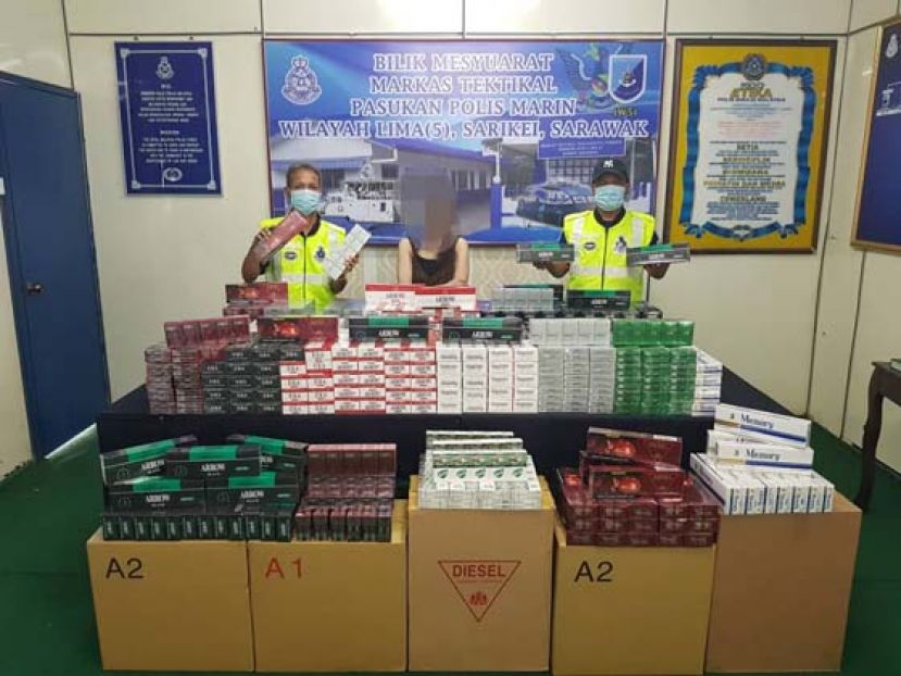 泗里街水警展示起获的私烟酒和扣押的妇女（中）。