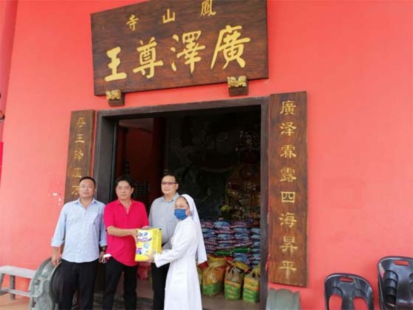 古晋毕打拿忠福宫广泽尊王庙理事会主席许义华（右2）布施食品予砂济世之家负责人费丽修女；右1为该庙副主席甲必丹陈国璋；左2是薛华东代表王运才博士。