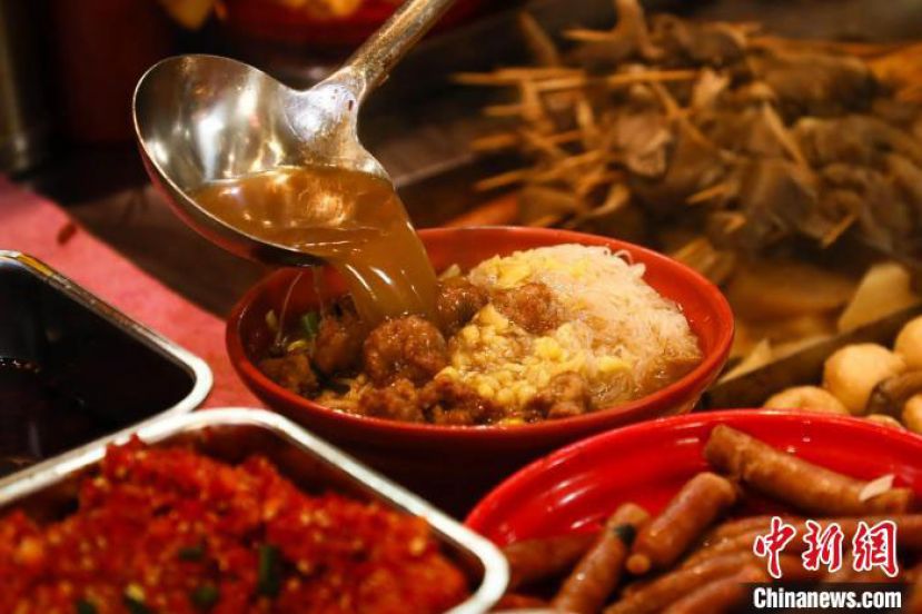 在南昌一家水煮店内，店员正在把汤汁浇至食材上。